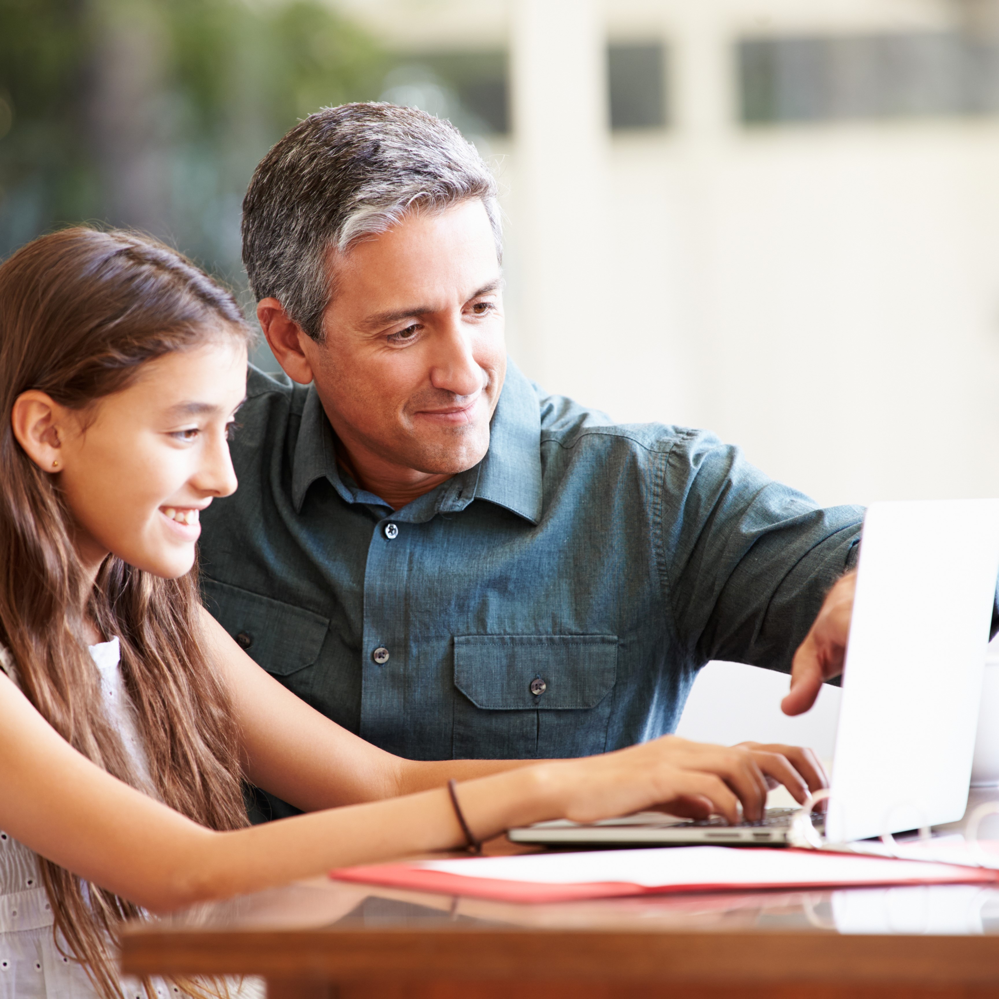 Père et sa fille qui sourient devant un ordinateur